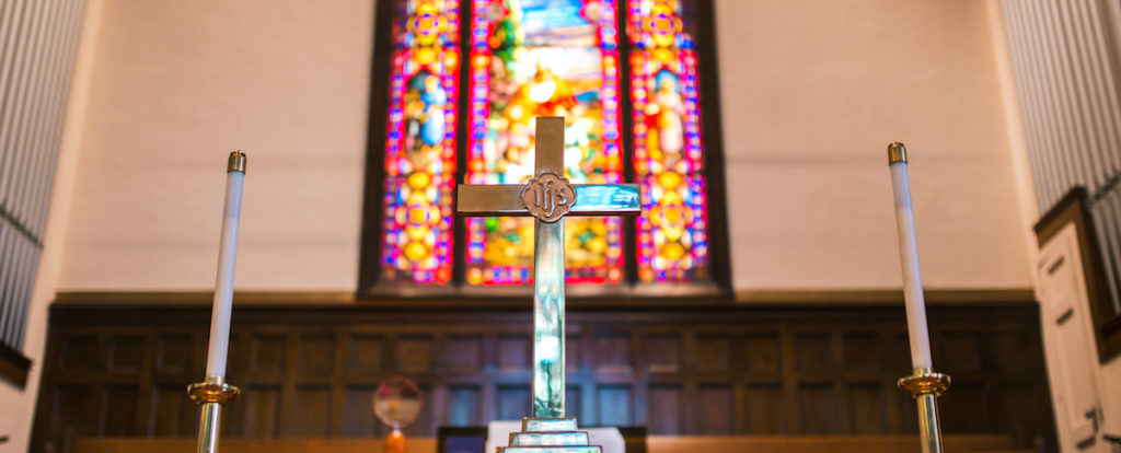 Cross on chancel with stained glass backdrop
