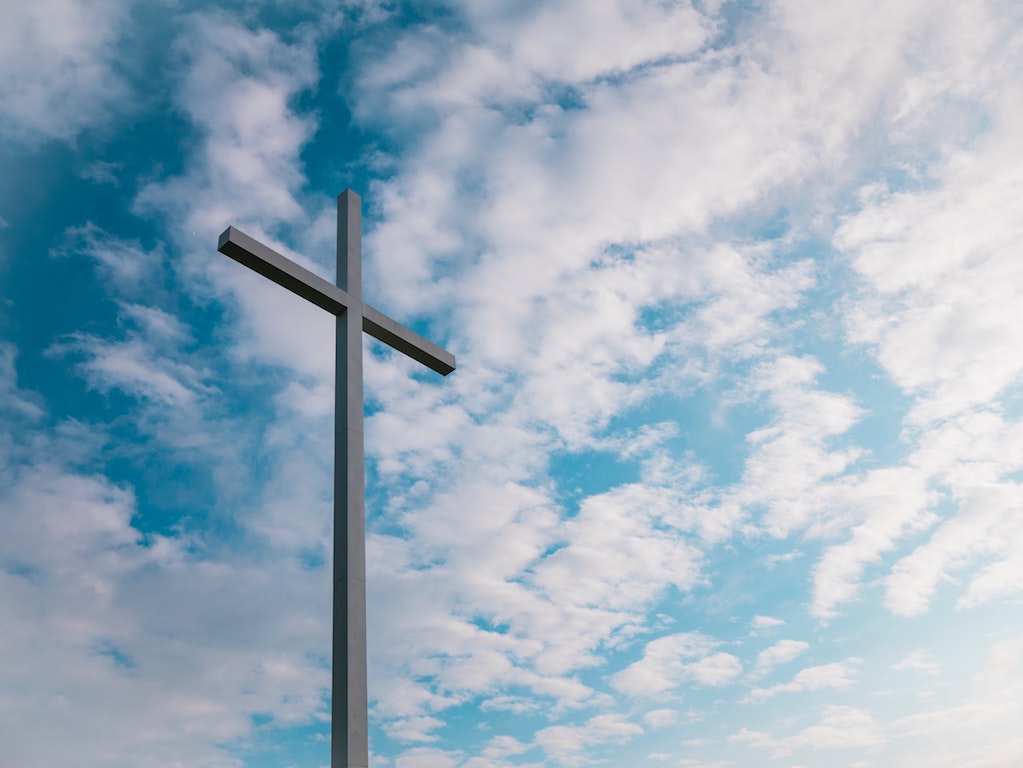 Very tall cross against a blue sky with mottled clouds